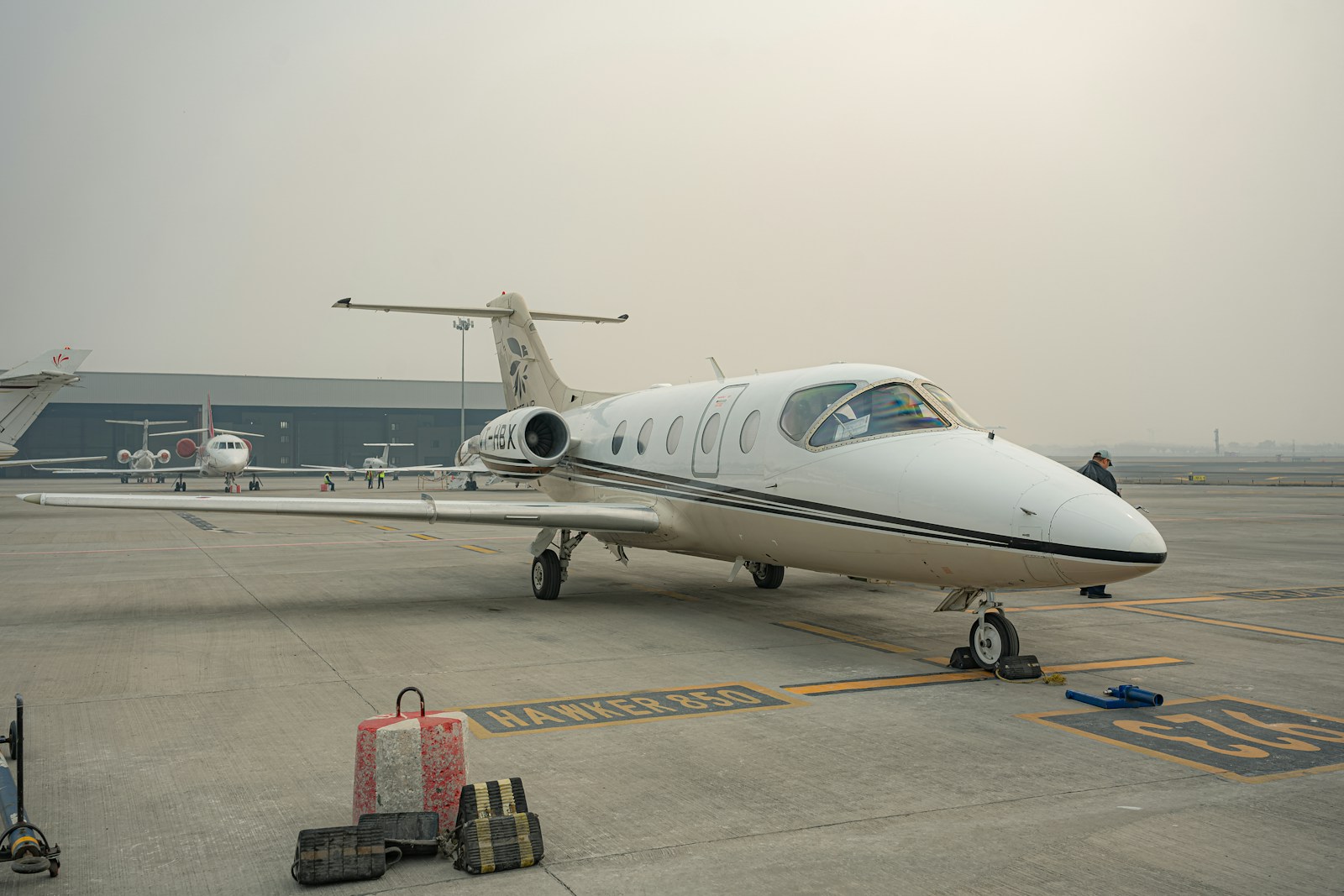 Light jet on a hazy apron with luggage being loaded